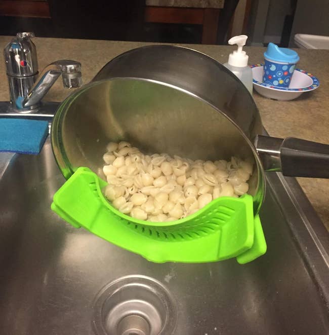 reviewer photo of the green strainer attached to the side of a pot, showing all the water has been strained out but the macaroni shells are still in the pot