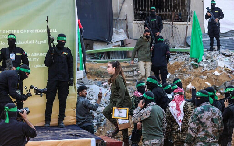 Hostage soldier Agam Berger is escorted onto a stage in northern Gaza's Jabalia, surrounded by Hamas gunmen, before she is handed over to the Red Cross on January 30, 2025 (Omar AL-QATTAA / AFP)