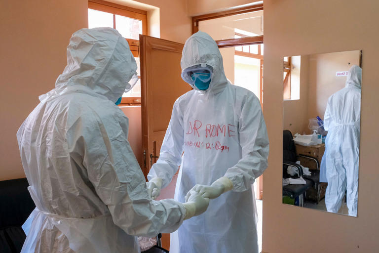 Doctors wearing protective equipment pray together before they visit a patient who was in contact with an Ebola victim, in the isolation section of Entebbe Regional Referral Hospital in Entebbe, Uganda on Oct. 20, 2022 (Copyright 2022 The Associated Press. All rights reserved.)