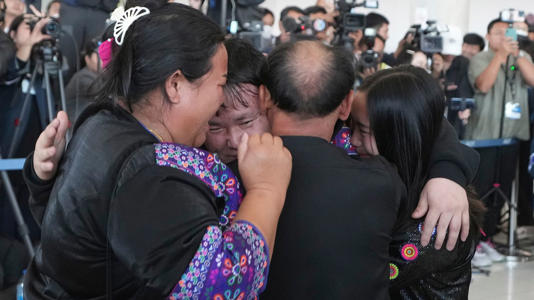 Bannawat Saethao (second from left) hugs relatives at the airport. Pic: AP