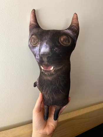 Plush toy shaped like a cat's head with exaggerated eyes and ears