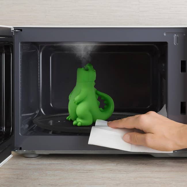 Green dinosaur-shaped microwave cleaner steaming inside a microwave