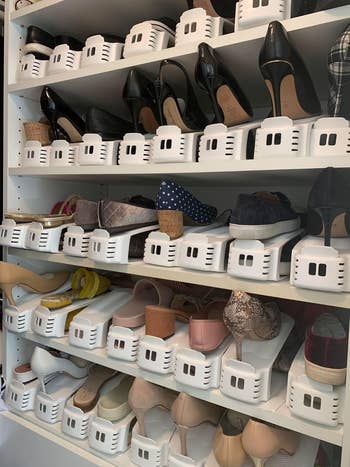 Closet with multiple shelves displaying various women's shoes, neatly organized with shoe stackers