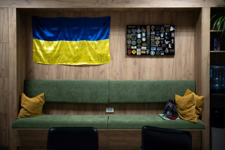 Un drapeau ukrainien signé par des soldats et des écussons militaires collés au mur d'une salle d'attente du bureau de l'ONG locale Veteran Hub, à Vinnytsia, le 4 février 2025 en Ukraine