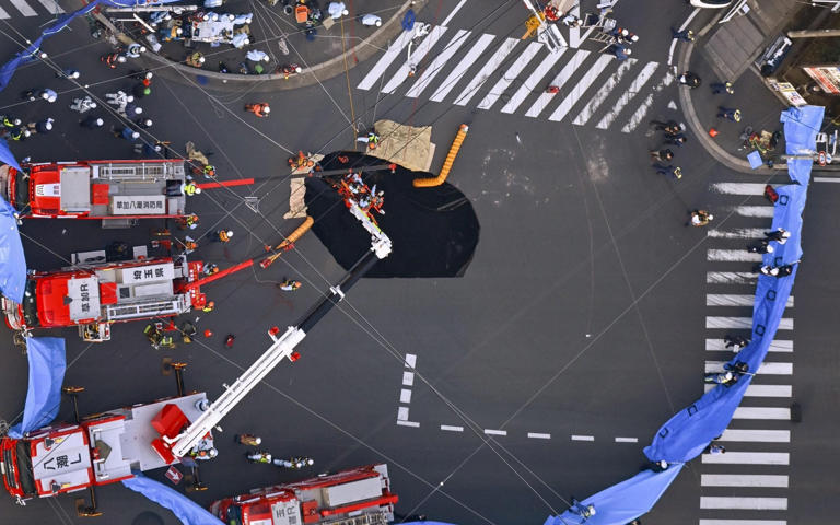 Emergency workers prepare to try and rescue a man in Yashio in the north-east of Tokyo - Kyodo/Newscom/Avalon