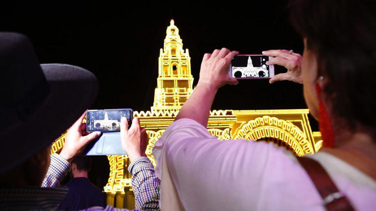 Dos mujeres hacen fotos a la portada de la Feria tras el alumbrado, en la edición del 2019. / MANUEL MURILLO