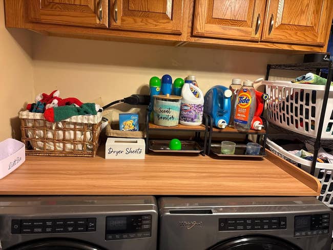 Laundry room counter with detergent bottles, dryer sheets, and folded clothes in a basket on washer dryer