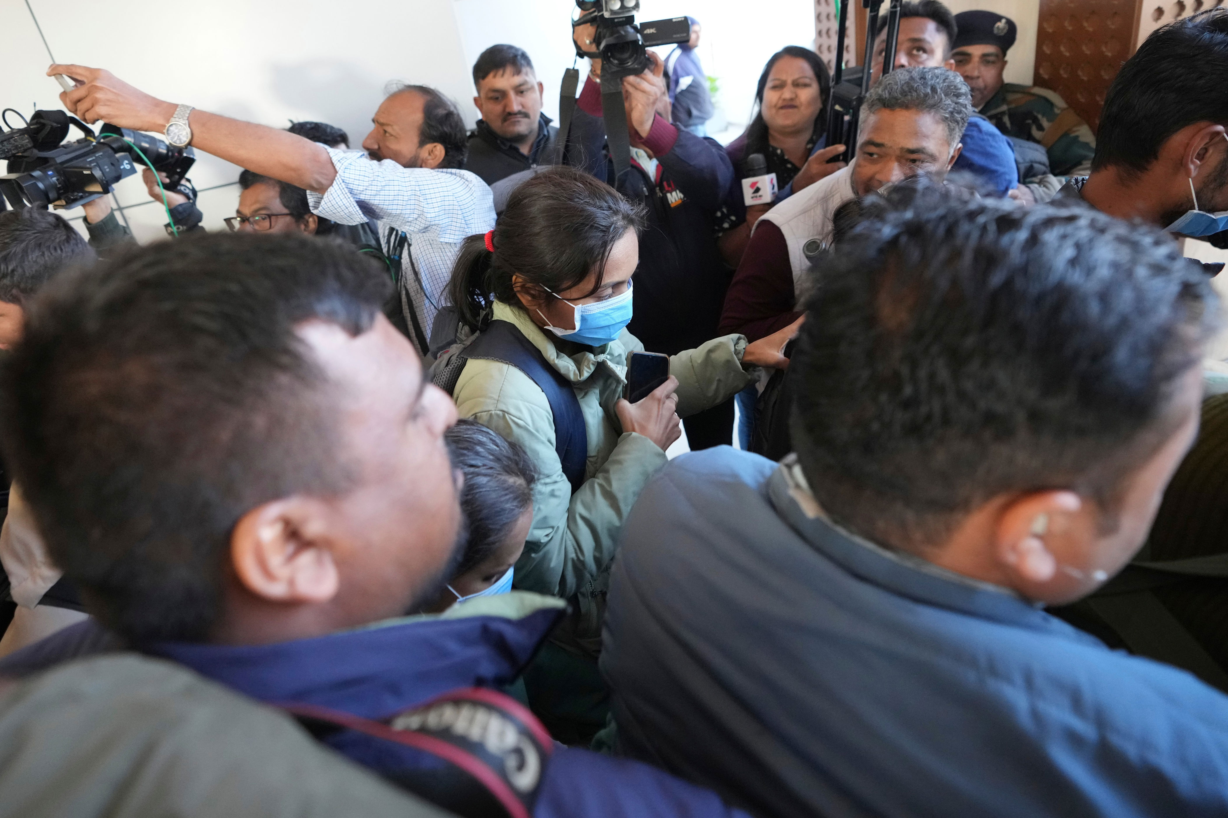 Indian police officials escort an immigrant woman, wearing mask, deported from the United States, right, who was among those who arrived in a U.S. military plane Wednesday in Amritsar, upon her arrival at the Ahmedabad airport in India, Thursday, Feb. 6, 2025. (AP Photo/Ajit Solanki)