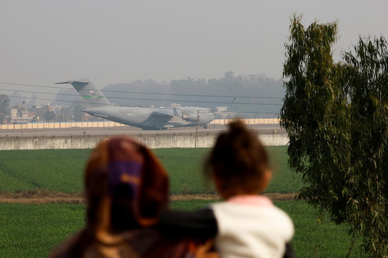 People look at a U.S. military plane deporting Indian immigrants as it lands in Amritsar, India February 5, 2025. REUTERS/Adnan Abidi