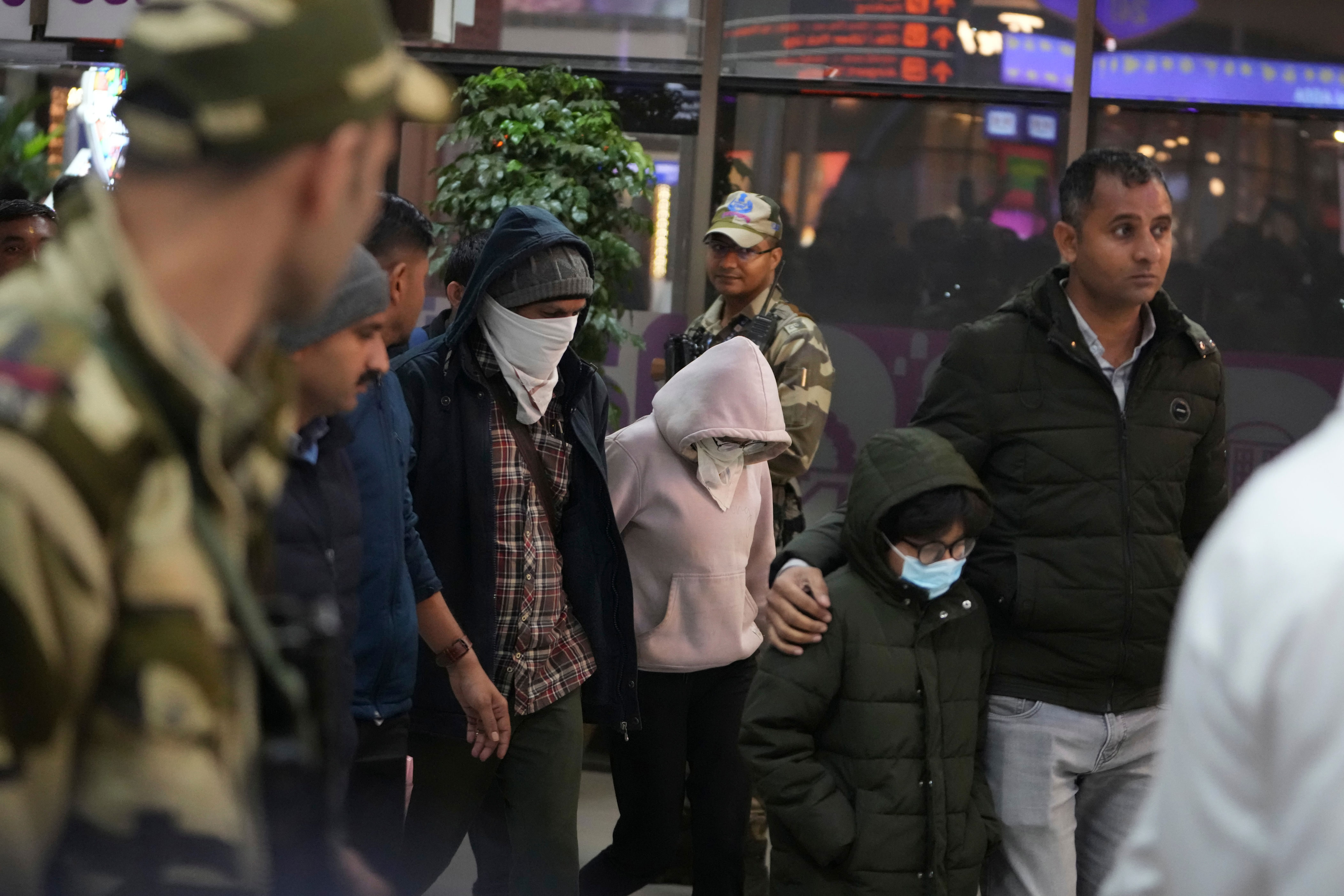 Indian police officials escort immigrants, wearing mask, deported from the United States, who were among those who arrived in a U.S. military plane Wednesday in Amritsar, upon their arrival at the Ahmedabad airport in India, Thursday, Feb. 6, 2025. (AP Photo/Ajit Solanki)