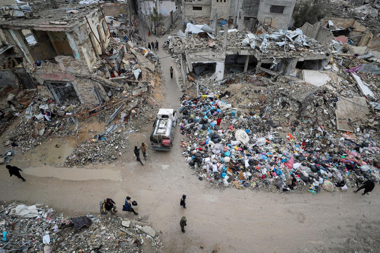 Palestinians walk past the rubble of buildings destroyed during the Israeli offensive, on a rainy day, amid a ceasefire between Israel and Hamas, in Gaza City February 6, 2025. REUTERS/Dawoud Abu Alkas TPX IMAGES OF THE DAY