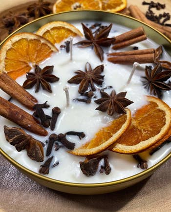 Decorative candle topped with dried orange slices, cinnamon sticks, star anise, and cloves
