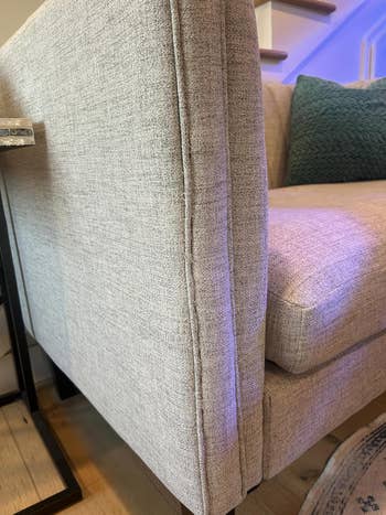 Elegant modern gray sofa with a textured finish in a cozy living room setting, accompanied by a dark green cushion on the seat