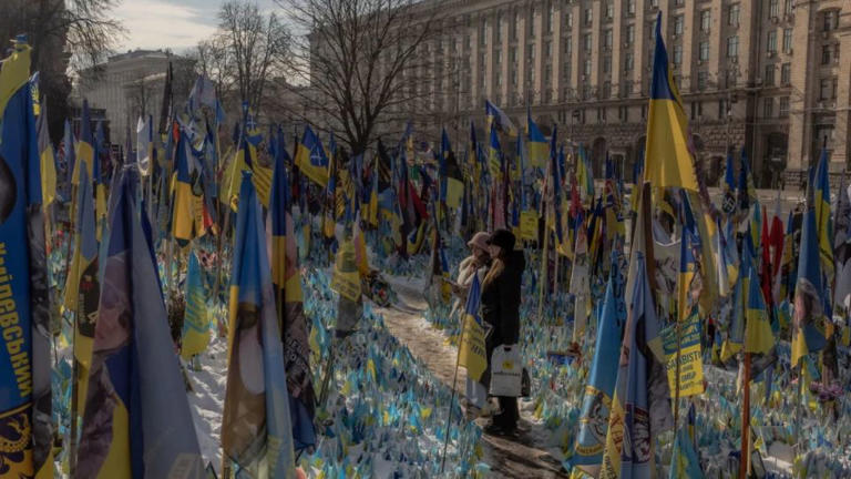 Visitantes se acercan a un memorial improvisado en homenaje a combatientes ucranianos y extranjeros en la Plaza de la Independencia de Kyiv, antes del tercer aniversario de la invasión de Ucrania por parte de Rusia. - Roman Pilipey/AFP/Getty Images