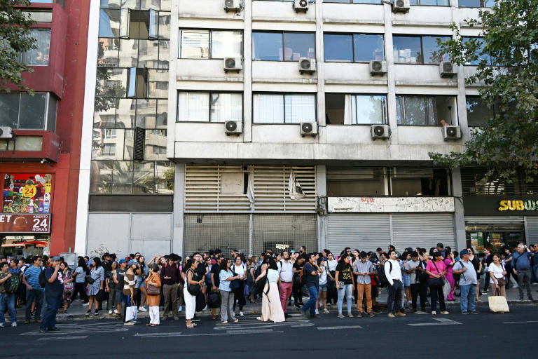 La gente espera en una parada de autobús durante un apagón en Santiago el 25 de febrero de 2025