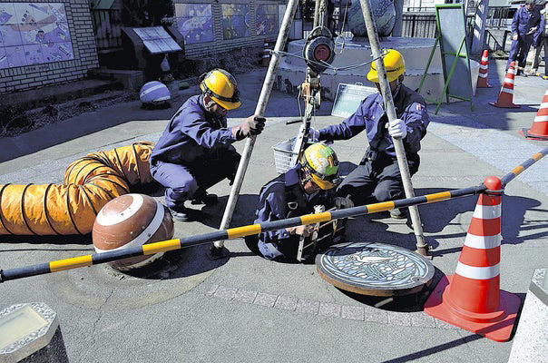 点検のため、マンホールを開け下水道の中に入る作業員（２６日、八潮市で）