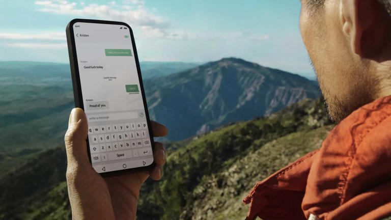 a person hiking holding a phone in hand using satellite sms messaging