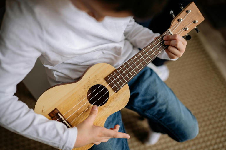 Un bambino suona l’ukulele (Pexels).