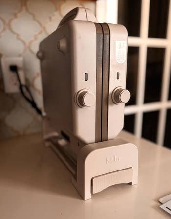 Vertical panini press on a kitchen counter, shown closed, highlighting its compact design suitable for easy storage