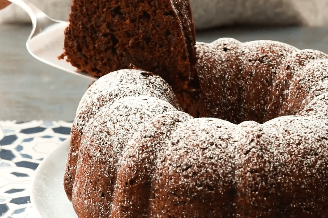 Chocolate Kahlua Cake with powdered sugar sifted overtop and a slice is being cut