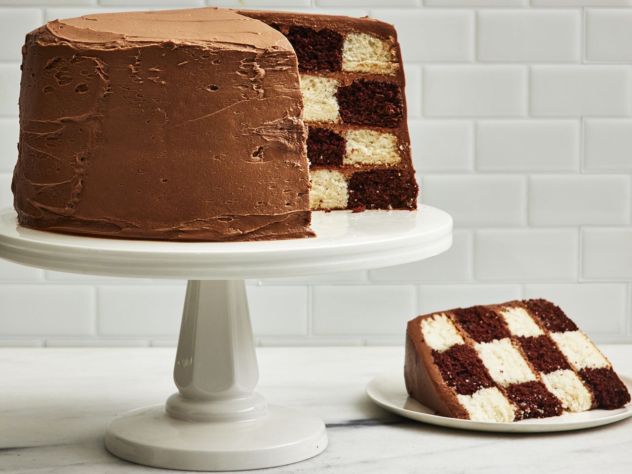 low angle looking at a checkerboard cake on a cake stand with a slice off to the side on a plate