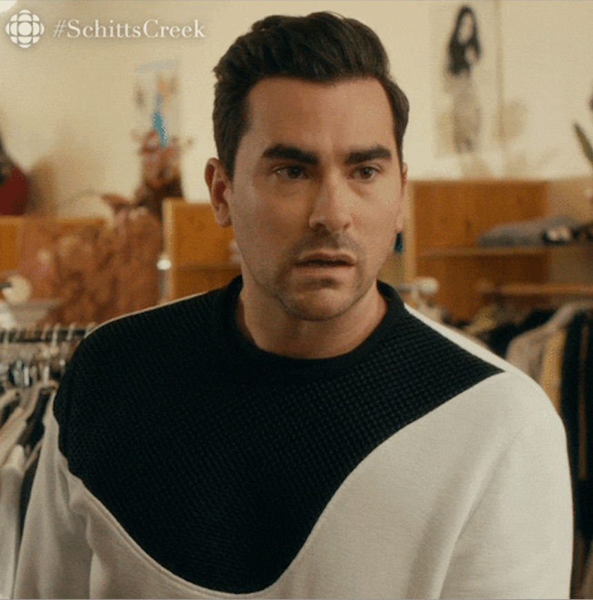 Person looking surprised, wearing a black and white sweater, standing in a clothing store
