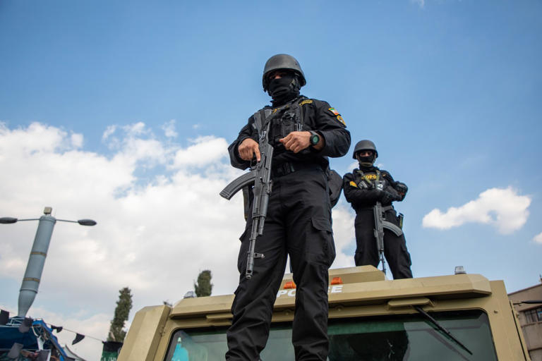 Members of security forces look on during a funeral procession.
