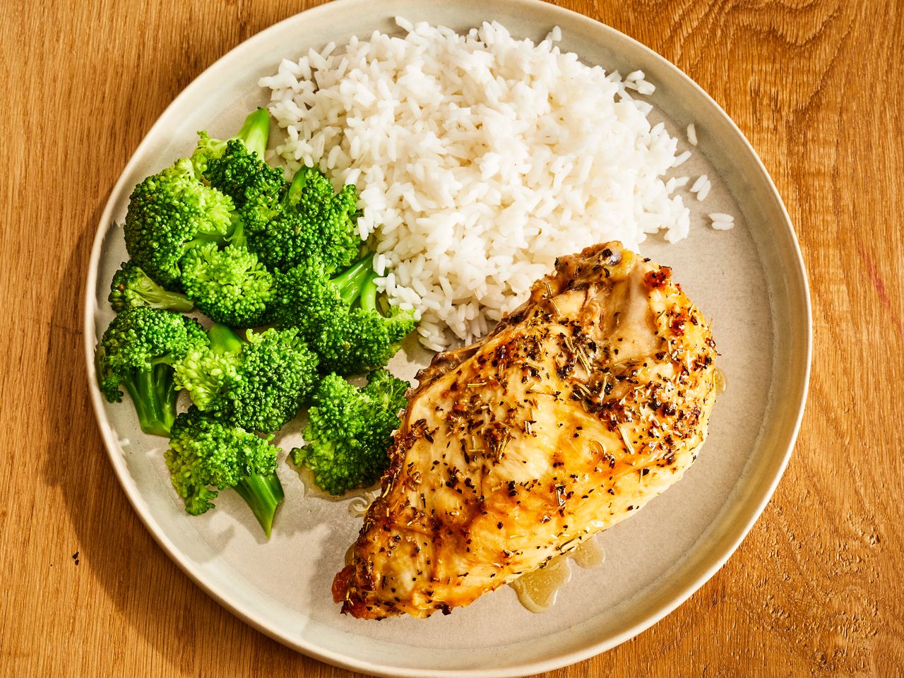Completed baked split chicken breast with broccoli and rice on the side.