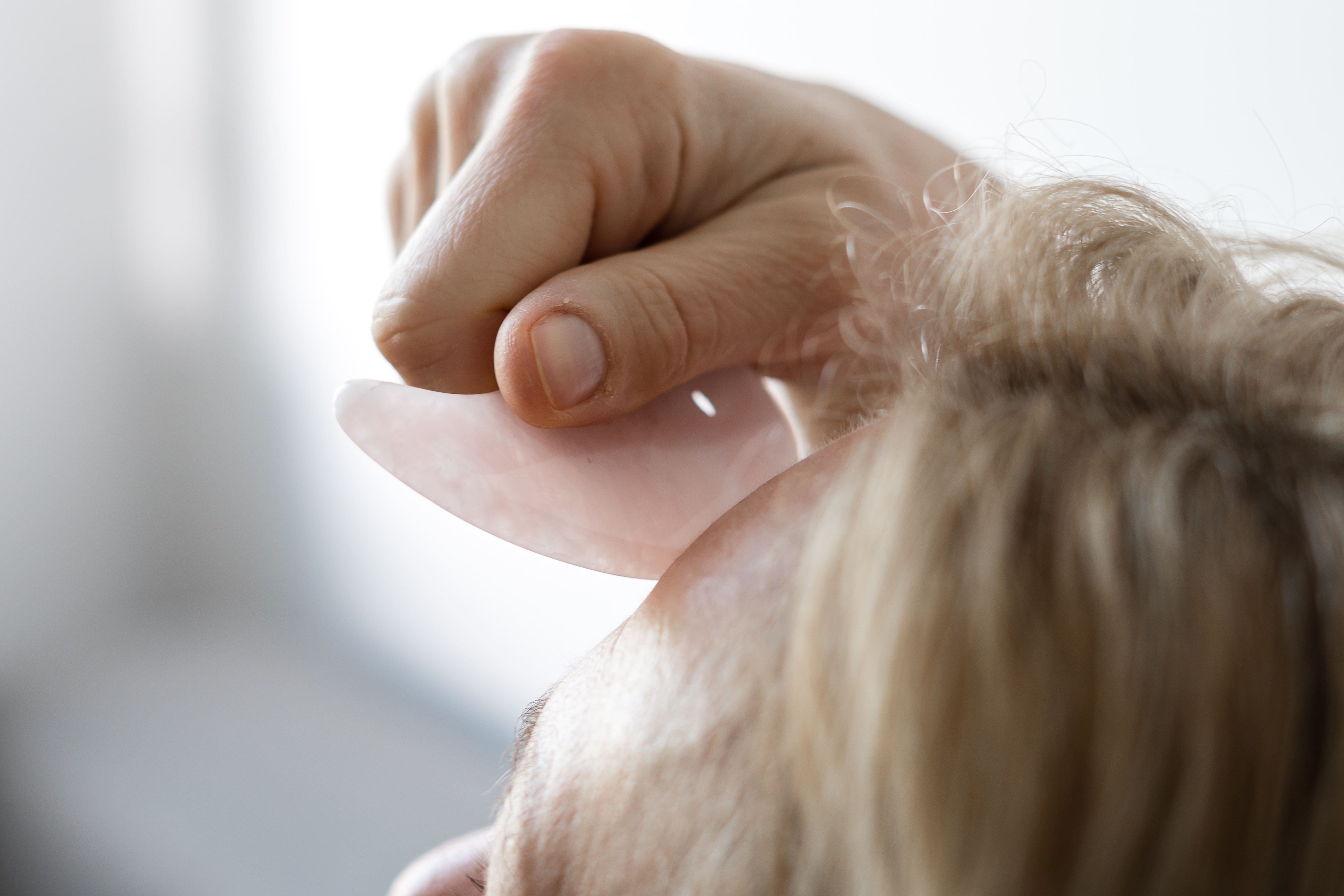 Person using a gua sha tool on their forehead, focusing on gentle skincare and massage