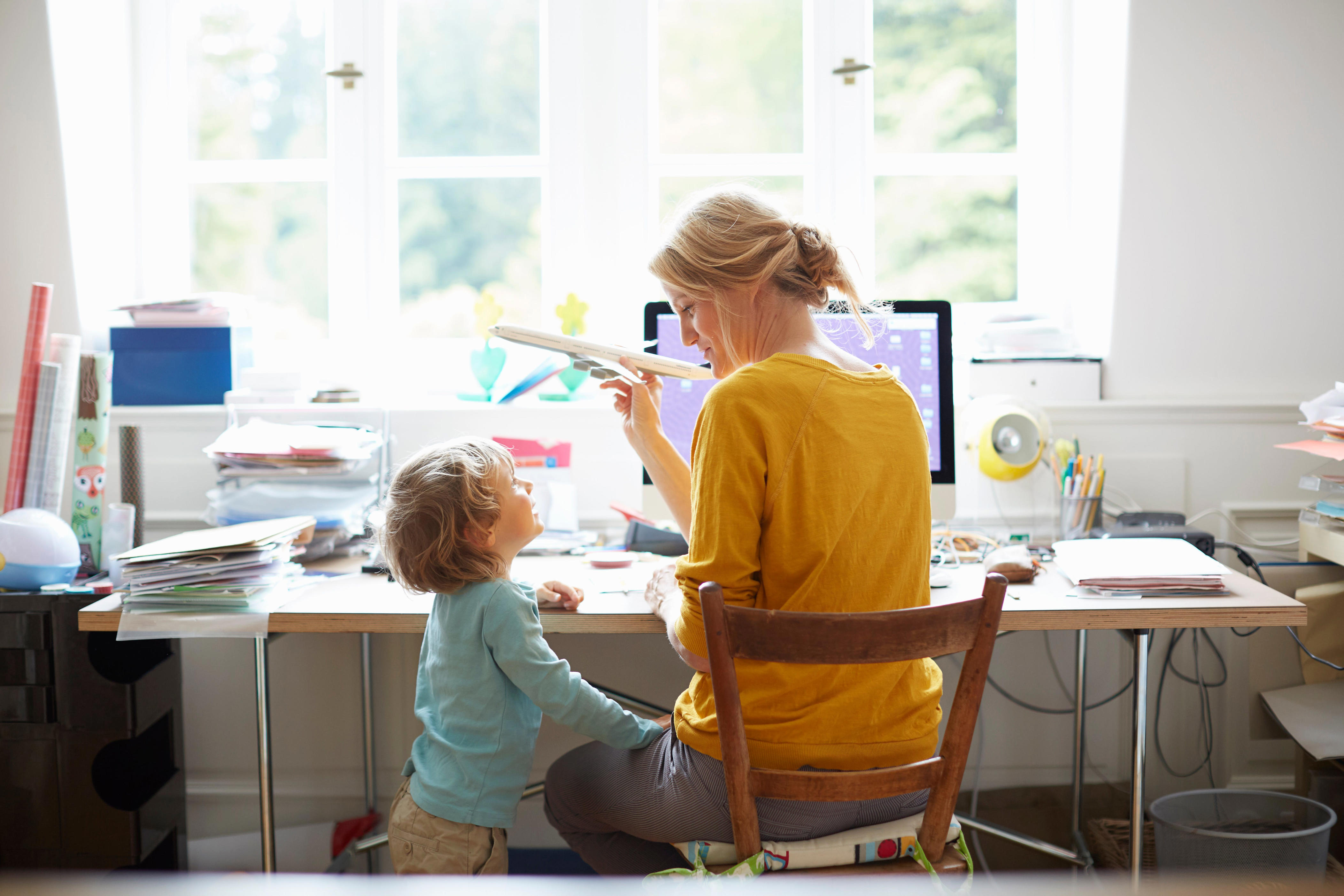 a woman at her desk while also playing with her son