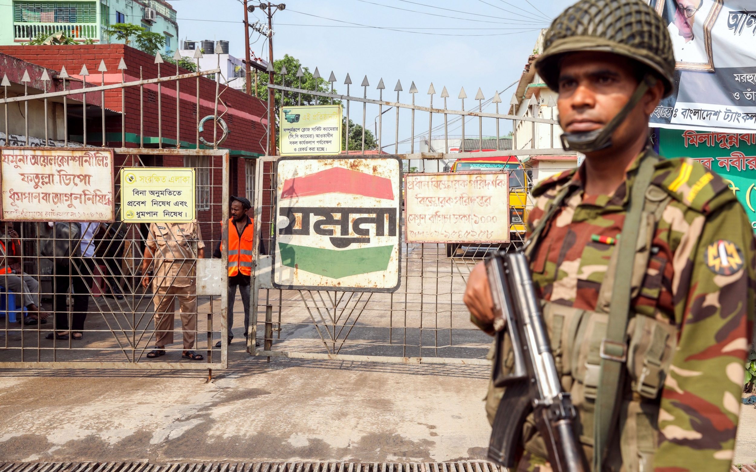 A member of Bangladeshi security forces guarding the entrance to an oil depot as fuel distributions becomes unstable - Monirul Alam/Shutterstock