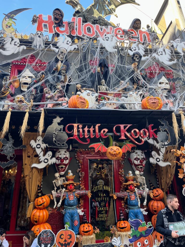 Halloween themed storefront covered in skeletons pumpkins cobwebs and ghost decorations with a large sign reading