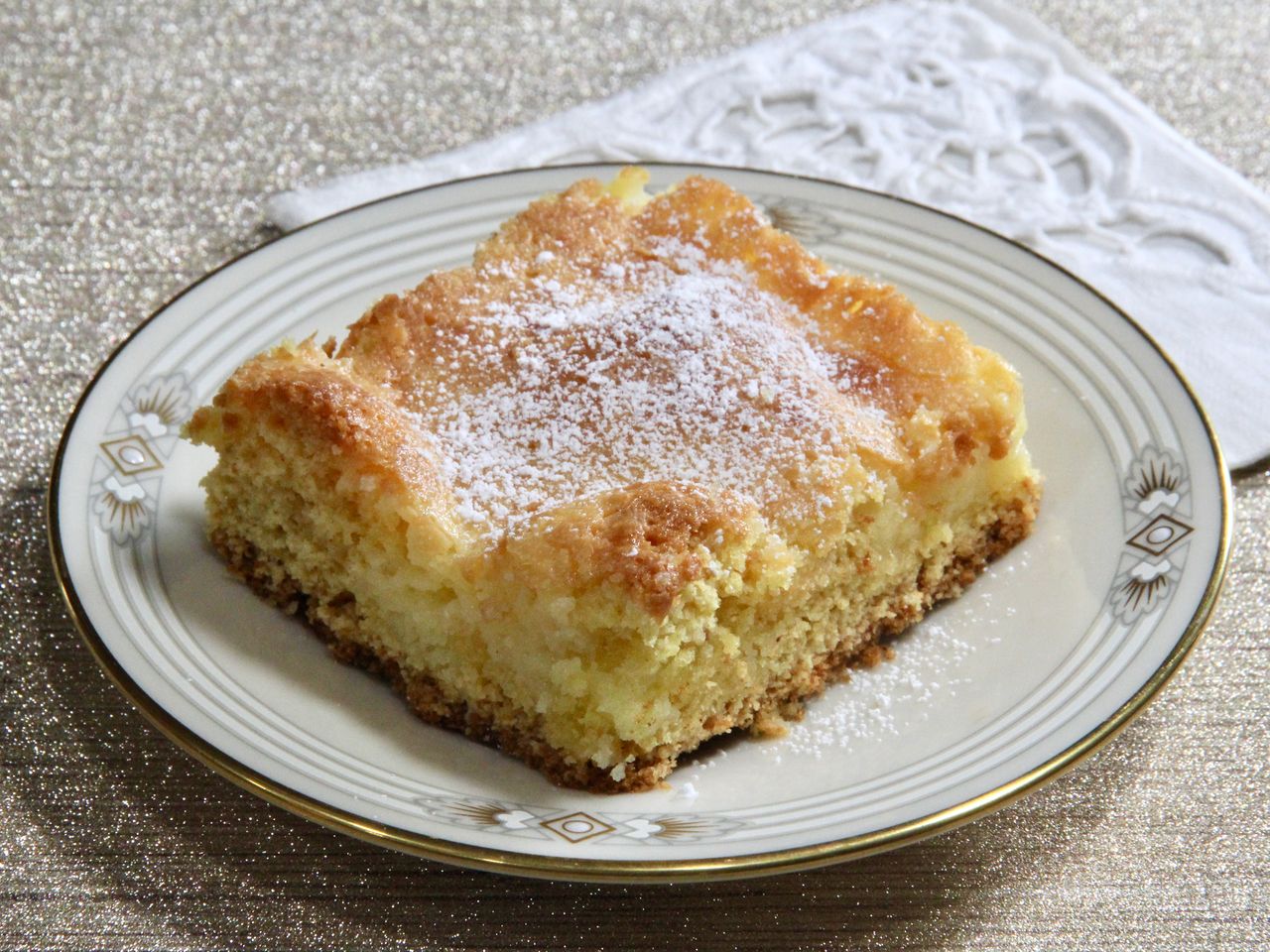 Slice of chess cake dusted with powdered sugar on white plate