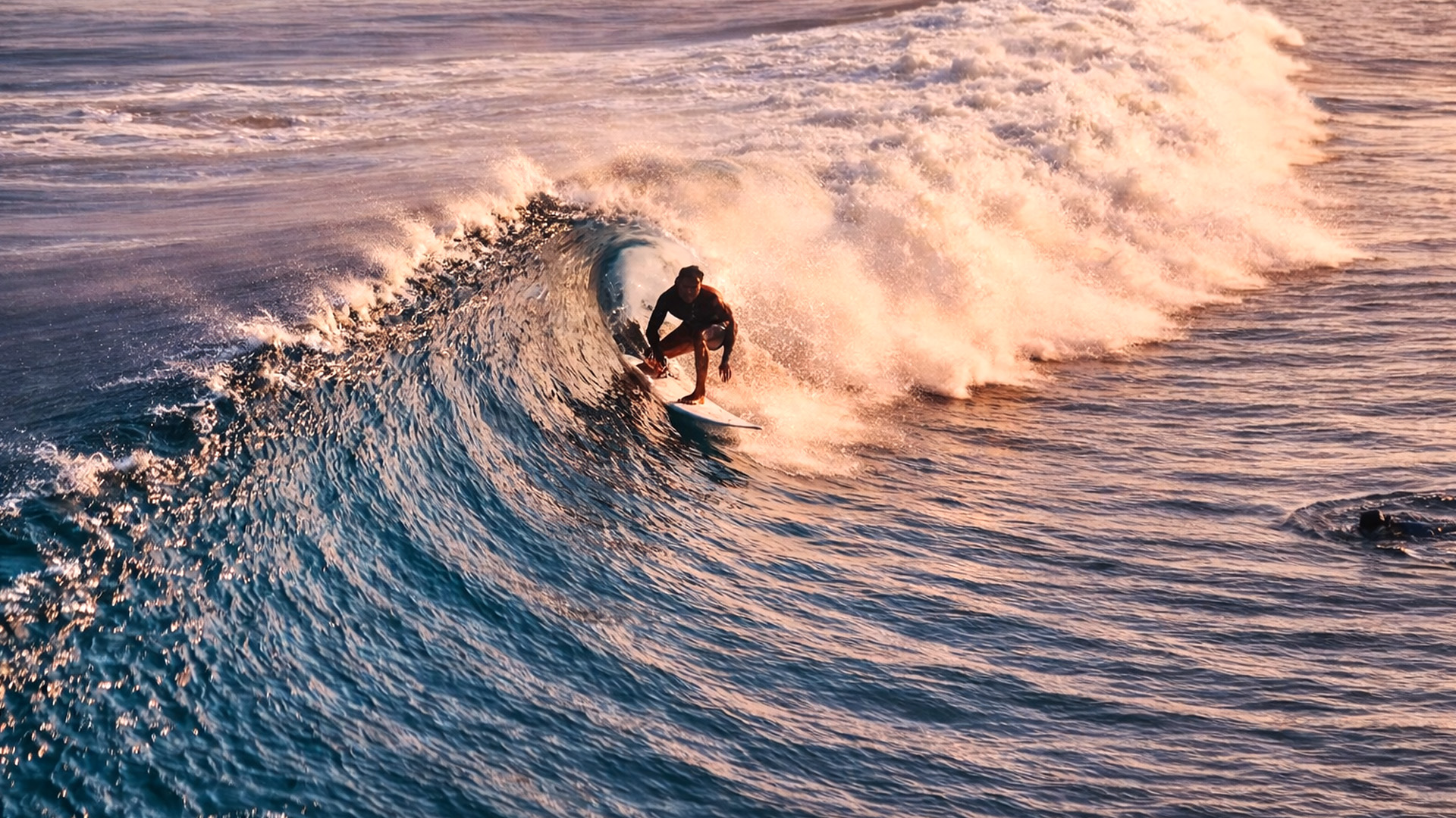 Surfistas surfeando olas perfectas bajo la luz dorada del atardecer