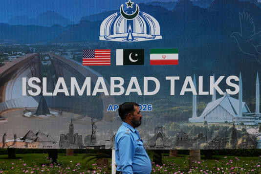 Một cảnh sát đi ngang qua tấm bảng thông báo về cuộc đàm phán giữa Mỹ và Iran tại Islamabad, Pakistan ngày 11/4. Ảnh: AP