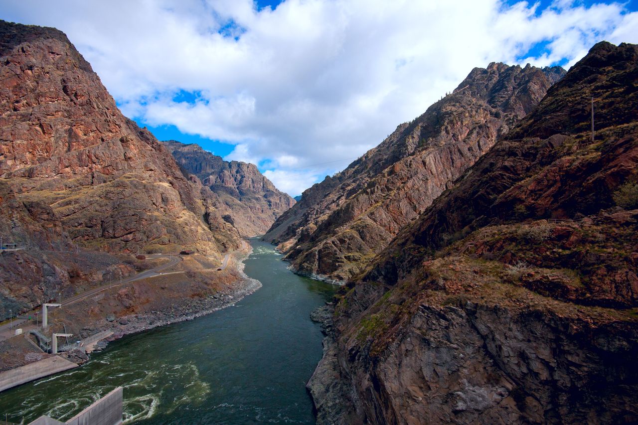 A canyon with a river flowing between high rocky cliffs under a partly cloudy sky