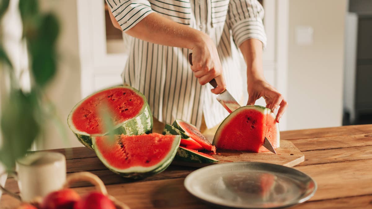 woman-cutting-watermelon-into-pieces-on-a-wooden-board