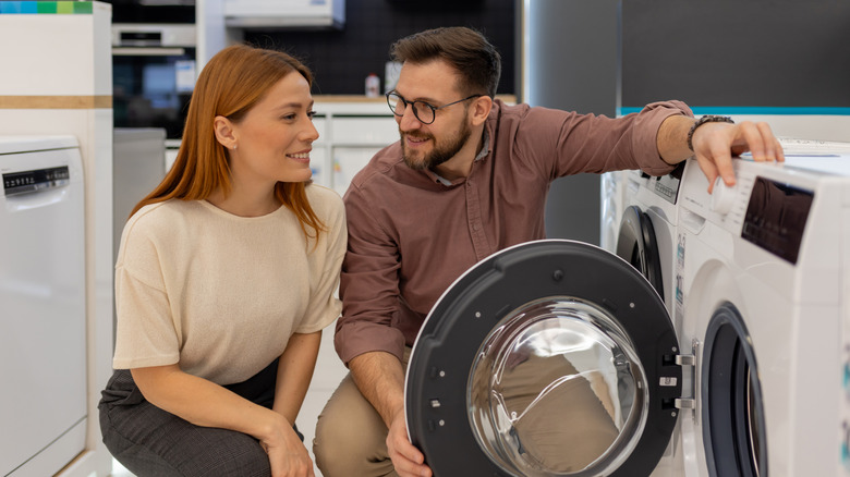 Happy couple looking at a clothes dryer in an appliance store