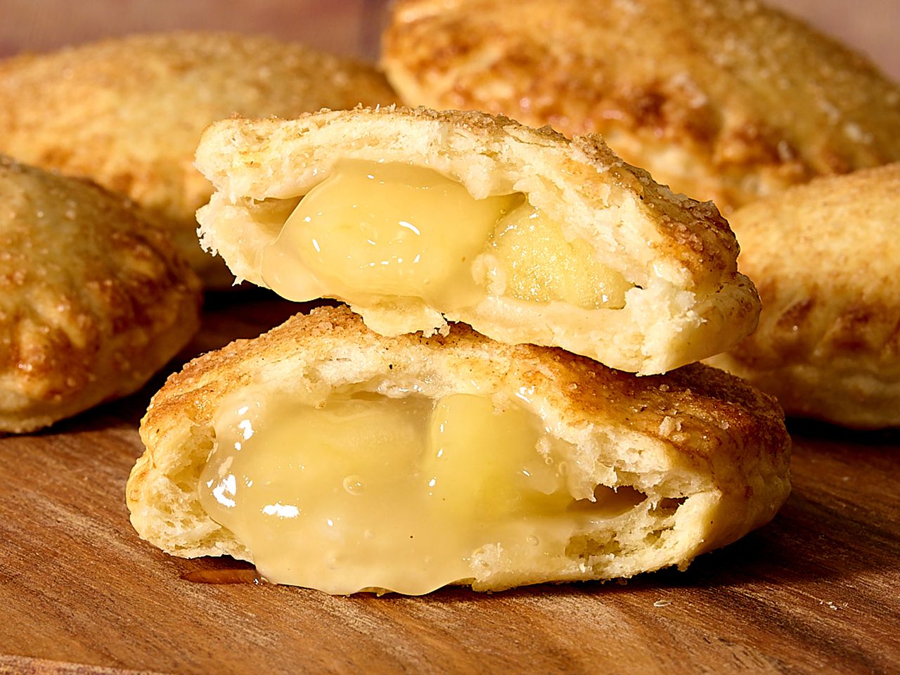 Two halves of an apple pie on a wooden surface