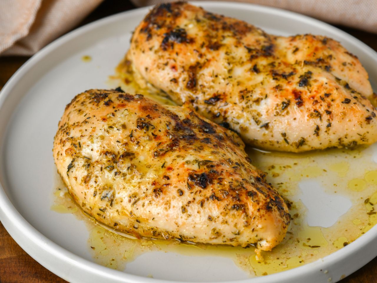 Herbed baked chicken breasts on white plate