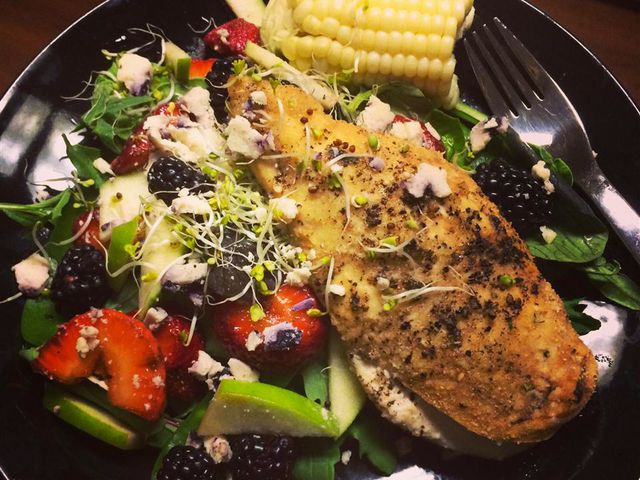 close up view of a Balsamic Goat Cheese Stuffed Chicken Breast served with salad and corn on the cob, on a plate