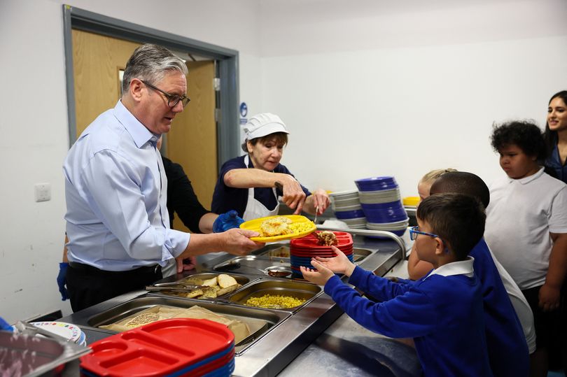 Britain's Prime Minister Keir Starmer serves lunch to school children