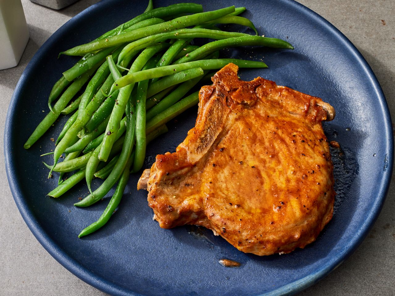 looking down at a plate of slow cooker bbq pork chops with a side of green beans