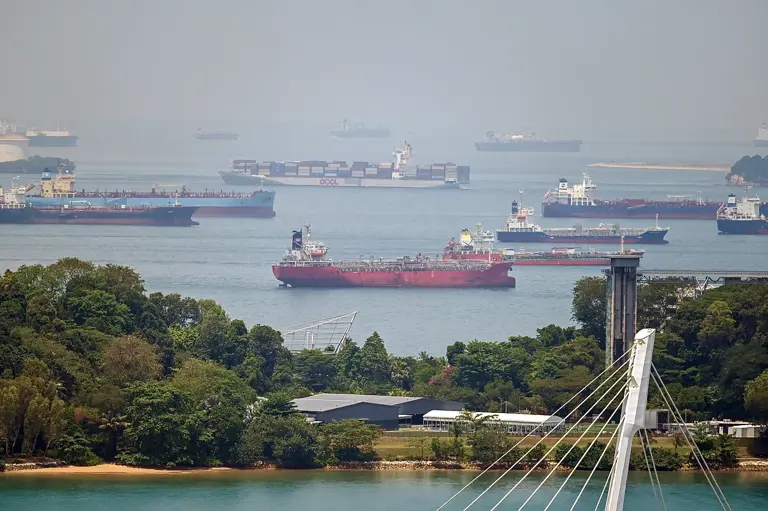 A container ship (top C) sails past oil tankers anchored along Singapore straits in Singapore on April 14, 2026.