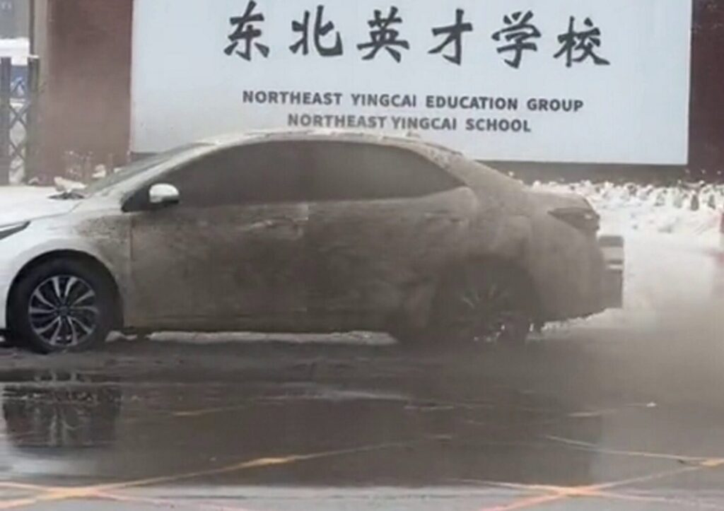 Spotless white car drenched in slush by passing snowplow