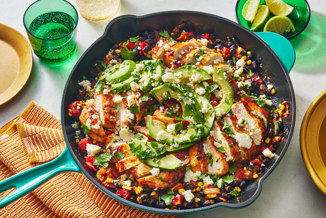 Cowboy Chicken in the skillet to serve, topped with cheese, cilantro, and sliced avocado