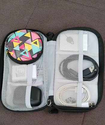 reviewer's travel tech organizer with various cables, charger, and a colorful geometric-patterned pouch. Ideal for gadget storage and convenience