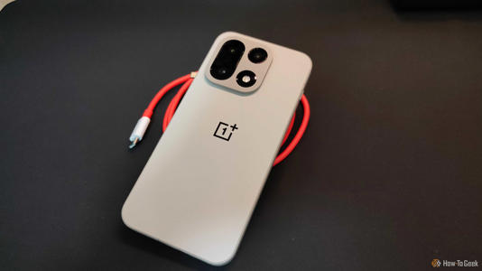 The OnePlus 15 resting against a red cable.