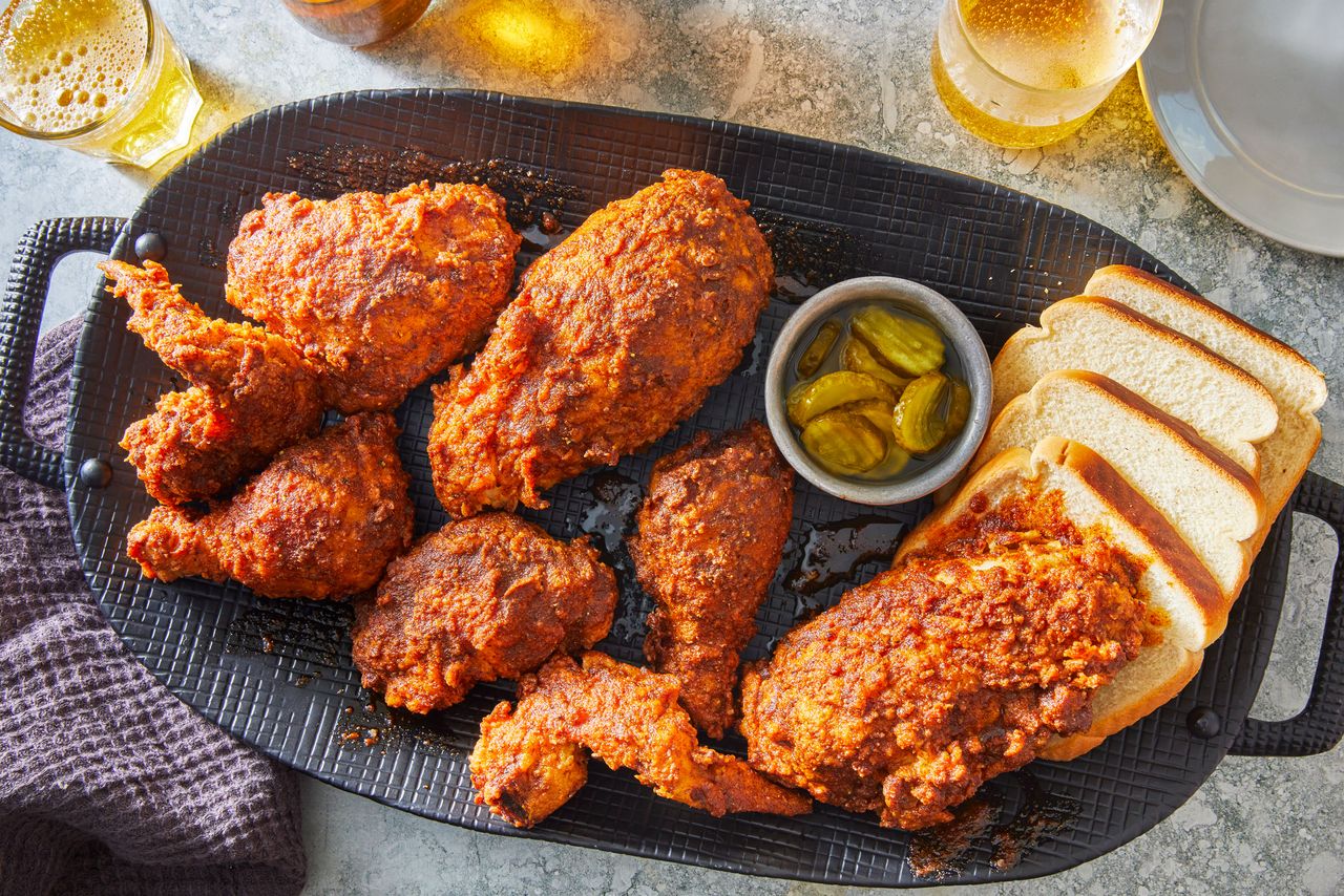 Southern Living Nashville Hot Chicken on a platter to serve with slices of bread, pickle slices, and glasses of beer