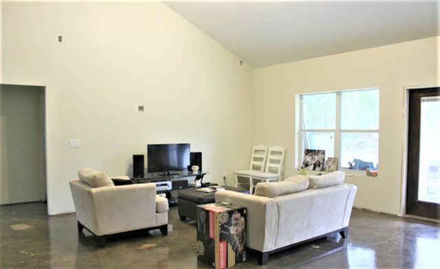 Living room with blank walls and vaulted ceiling with white chairs and love seat before makeover